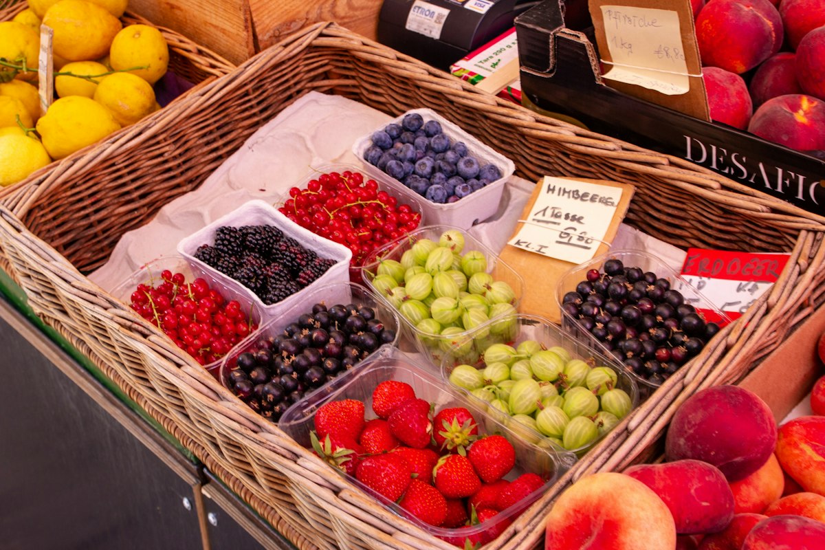 Erdbeeren, Johannisbeeren, Stachelbeeren und Heidelbeeren in Schälchen im Weidenkorb