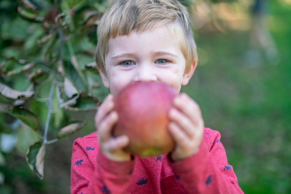 Kind hält einen roten Apfel